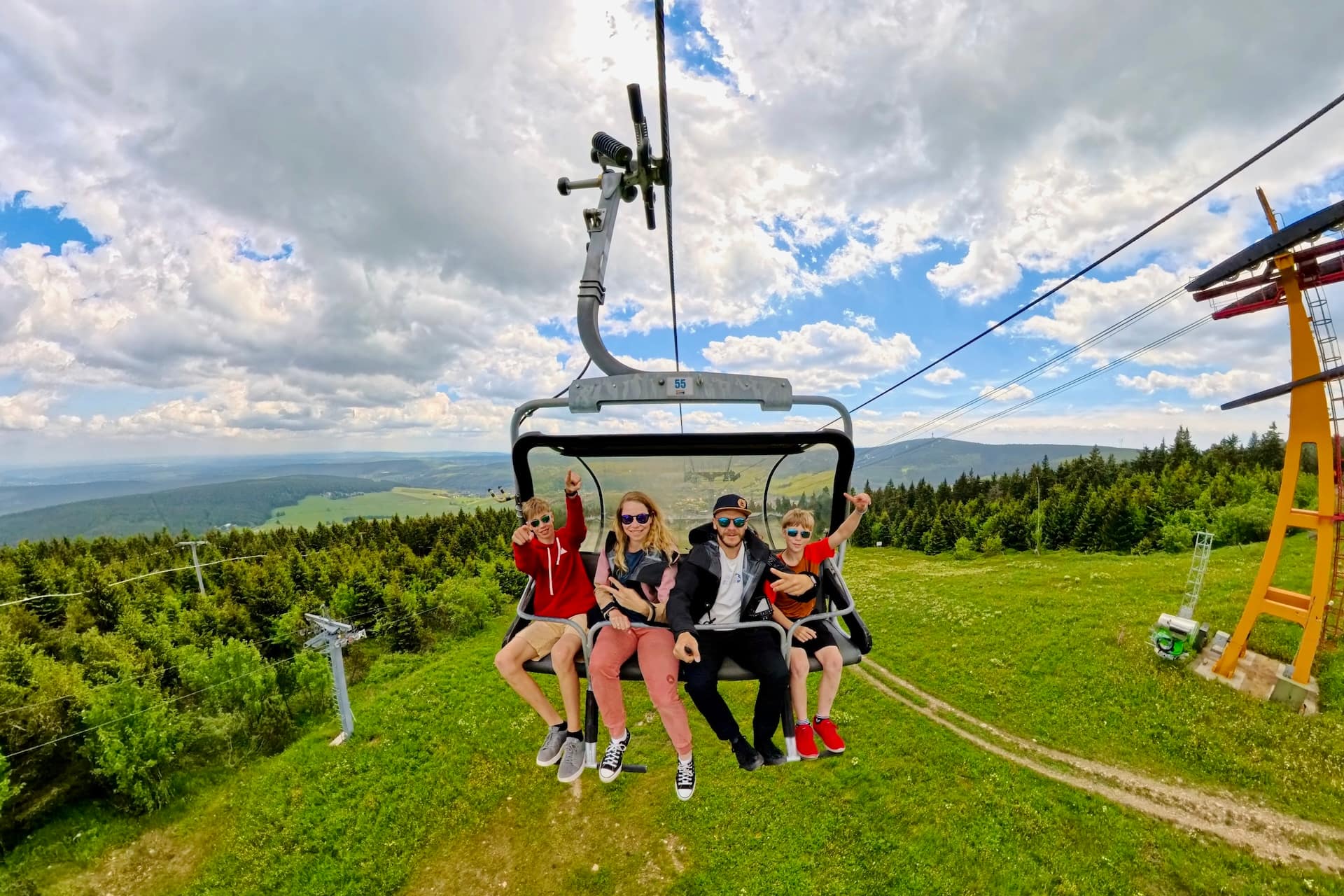 Familie zu viert im Sessellift über den grünen Hängen am Fichtelberg