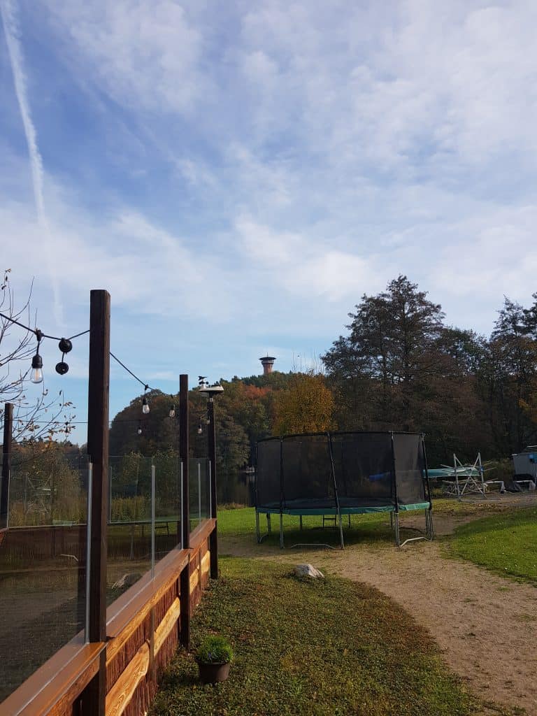 Trampolin auf einer Wiese am See, im Hintergrund der Aussichtsturm auf dem Jörnberg